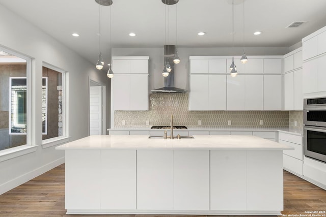 kitchen with tasteful backsplash, visible vents, wall chimney exhaust hood, modern cabinets, and wood finished floors