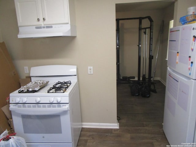 kitchen featuring under cabinet range hood, white appliances, dark wood-type flooring, baseboards, and white cabinets