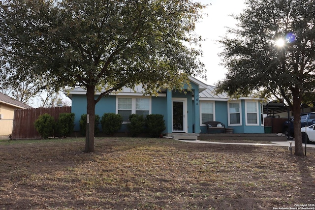 view of front facade with metal roof, fence, a standing seam roof, and stucco siding