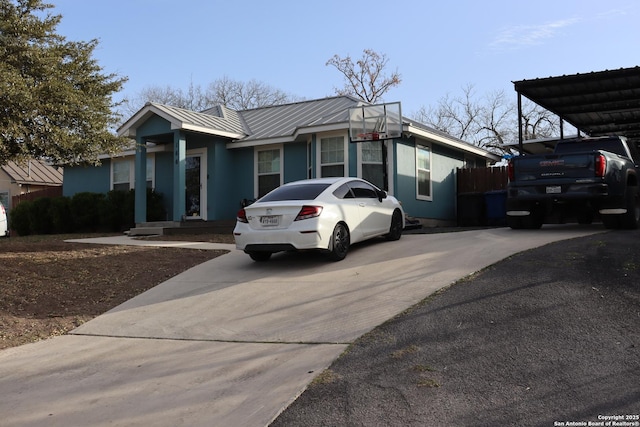 view of front of house featuring metal roof, a standing seam roof, and driveway