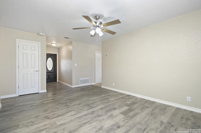 unfurnished room featuring wood finished floors, visible vents, and baseboards