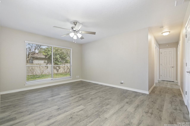 empty room featuring light wood finished floors, baseboards, and a ceiling fan