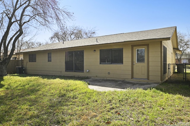 back of property with central AC unit, fence, a lawn, and a patio