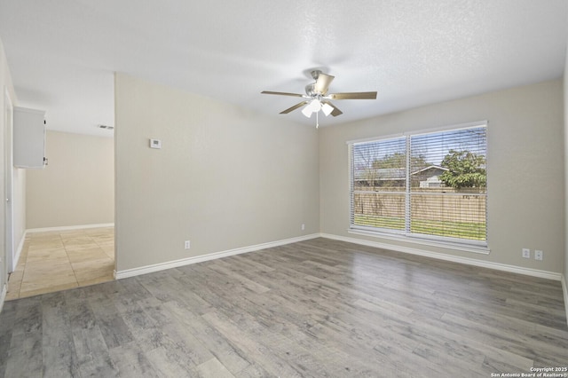 empty room featuring a ceiling fan, a textured ceiling, baseboards, and wood finished floors