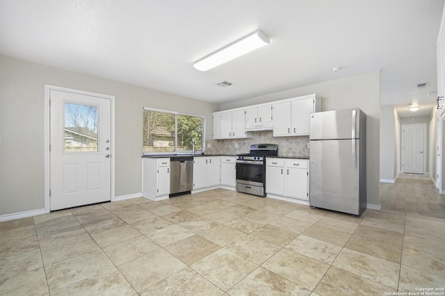 kitchen featuring tasteful backsplash, dark countertops, appliances with stainless steel finishes, under cabinet range hood, and white cabinetry