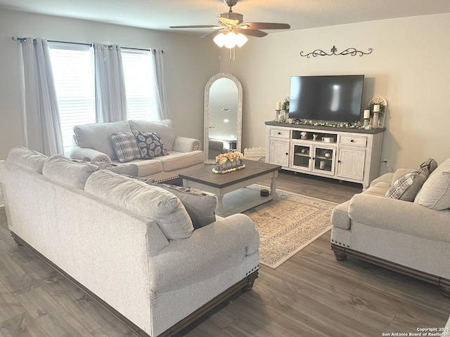 living area featuring a ceiling fan, arched walkways, and dark wood finished floors