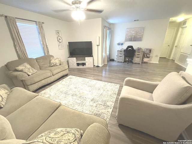 living room featuring wood finished floors, a ceiling fan, and baseboards