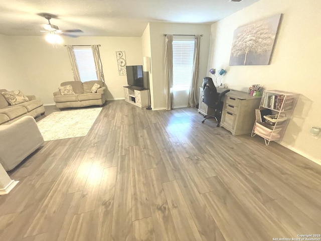 living room with wood finished floors, a ceiling fan, and baseboards