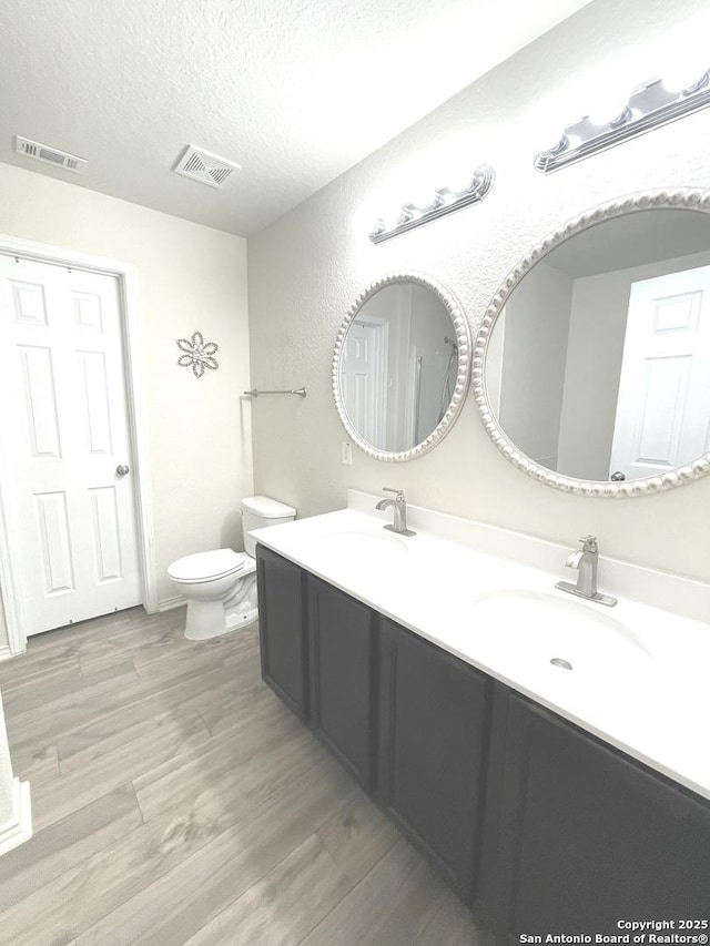 full bathroom featuring a textured ceiling, wood finished floors, a sink, and visible vents