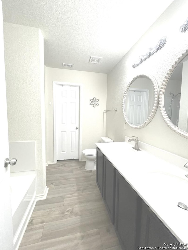 full bathroom with visible vents, a sink, a textured ceiling, and toilet