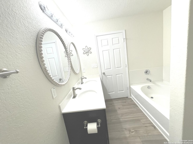 full bathroom with a textured wall, a sink, and a washtub