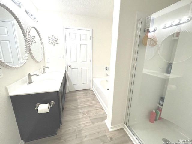 full bath with double vanity, wood finished floors, a garden tub, a shower stall, and a sink