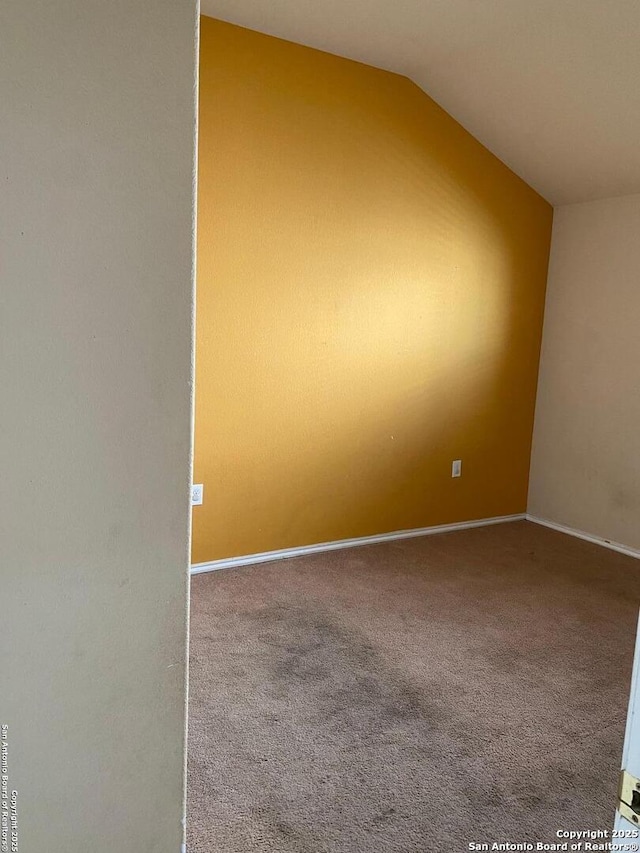 spare room with carpet, baseboards, and vaulted ceiling