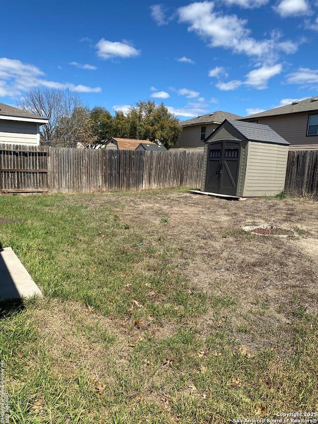 view of yard featuring an outbuilding, a fenced backyard, and a storage unit