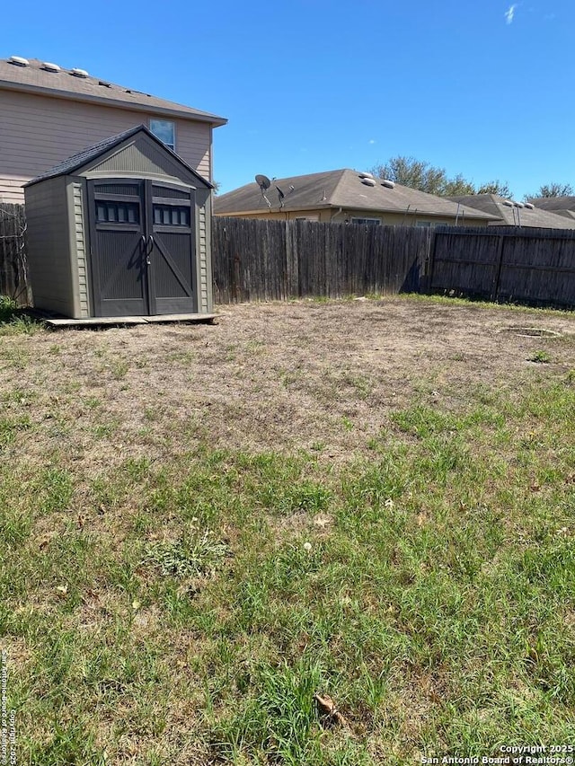 view of yard with fence, an outdoor structure, and a storage unit