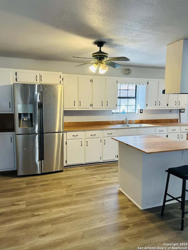 kitchen featuring light wood finished floors, butcher block countertops, white cabinetry, and stainless steel fridge with ice dispenser