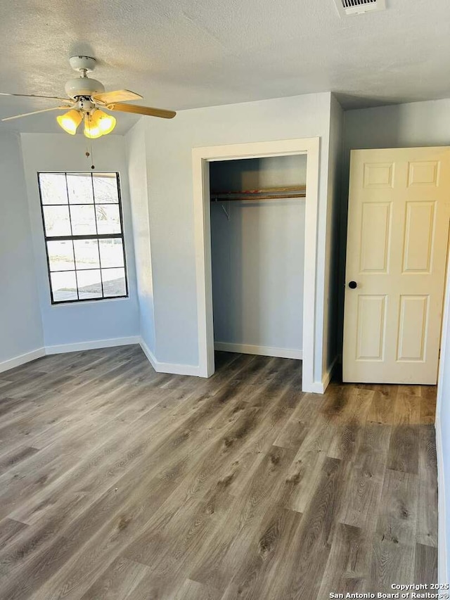 unfurnished bedroom with visible vents, baseboards, wood finished floors, a textured ceiling, and a closet