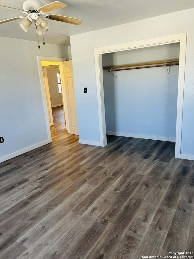 unfurnished bedroom with dark wood-style floors, a closet, ceiling fan, and baseboards