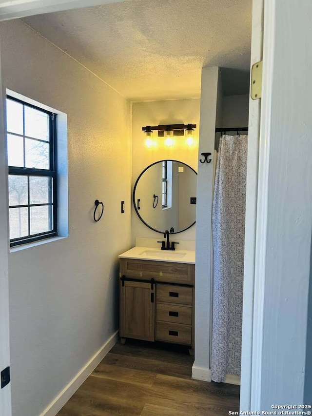 full bathroom featuring baseboards, a textured ceiling, vanity, and wood finished floors