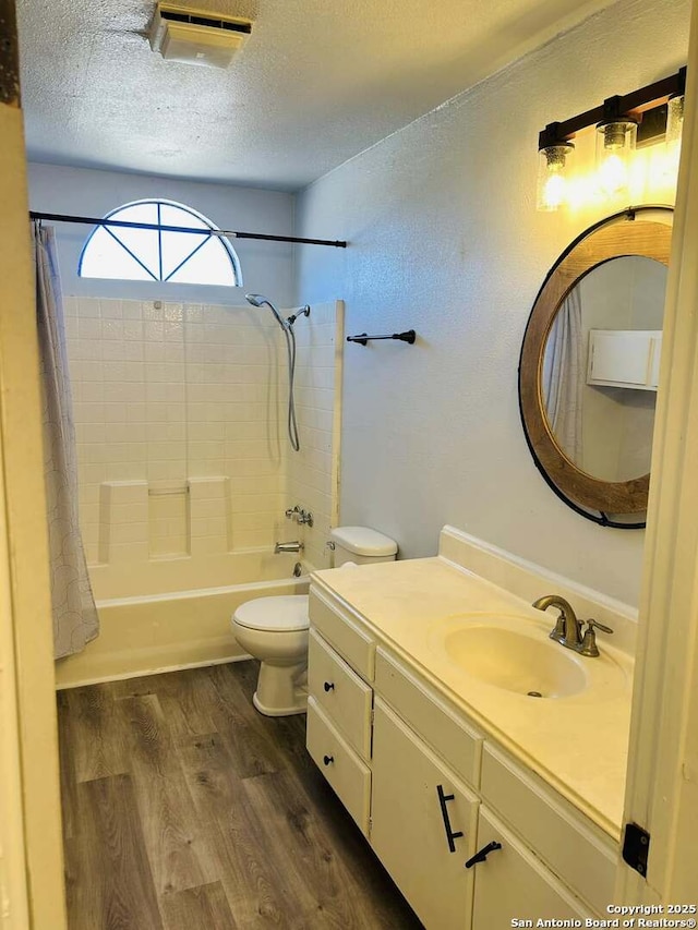 bathroom featuring shower / tub combo with curtain, toilet, vanity, a textured ceiling, and wood finished floors