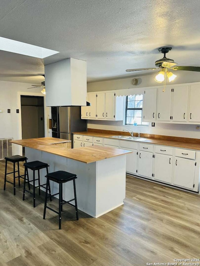 kitchen with butcher block countertops, light wood-type flooring, and white cabinets