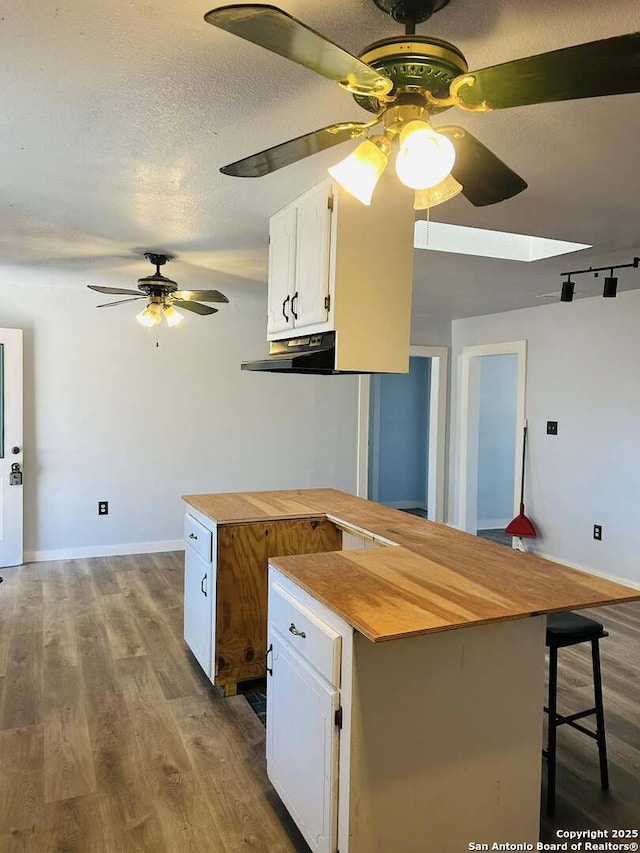 kitchen featuring white cabinets, wooden counters, a textured ceiling, and wood finished floors