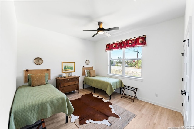 bedroom with light wood-type flooring, baseboards, and a ceiling fan