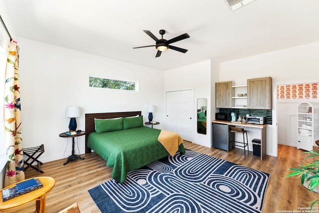 bedroom with baseboards, visible vents, light wood-style floors, ceiling fan, and fridge