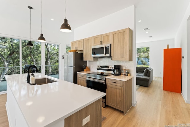 kitchen with stainless steel appliances, a sink, visible vents, light wood-type flooring, and backsplash