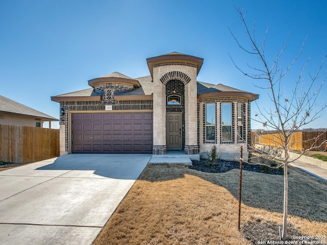 view of front of house featuring brick siding, driveway, an attached garage, and fence