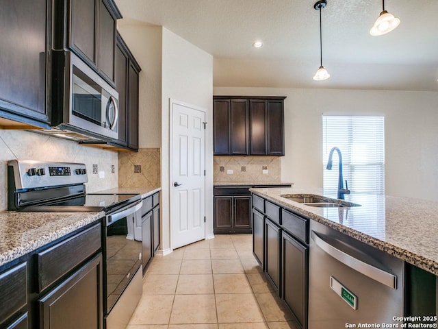 kitchen featuring tasteful backsplash, hanging light fixtures, appliances with stainless steel finishes, light tile patterned flooring, and a sink