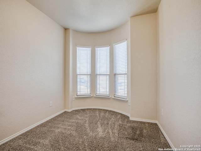 carpeted empty room featuring baseboards