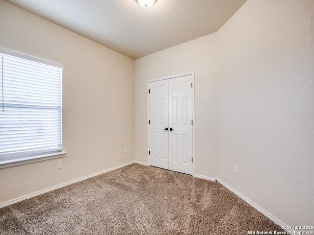 unfurnished bedroom with carpet, a closet, and baseboards