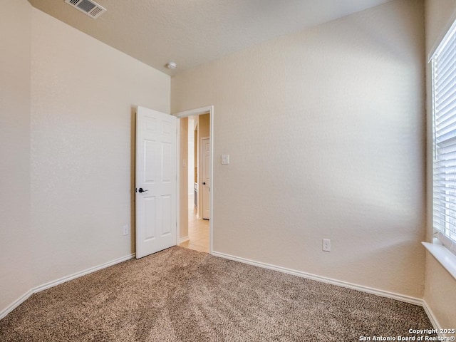 spare room featuring light carpet, baseboards, and visible vents