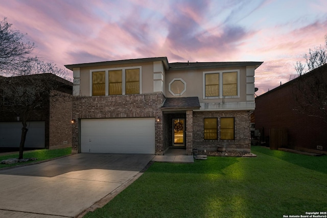 view of front of property featuring a garage, brick siding, concrete driveway, a yard, and stucco siding