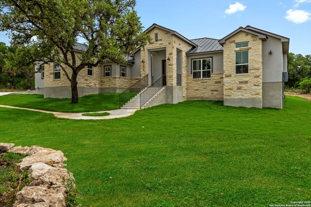 view of front of house with a standing seam roof, stone siding, a front lawn, and metal roof