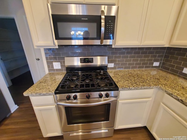 kitchen with stainless steel appliances, white cabinets, backsplash, and light stone countertops