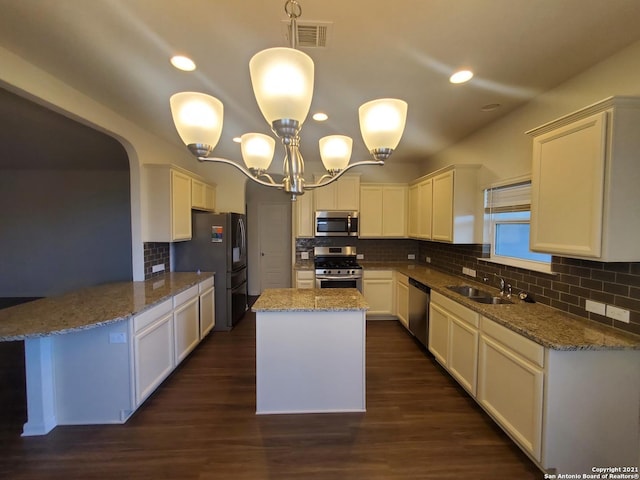 kitchen featuring light stone counters, a sink, visible vents, appliances with stainless steel finishes, and dark wood finished floors