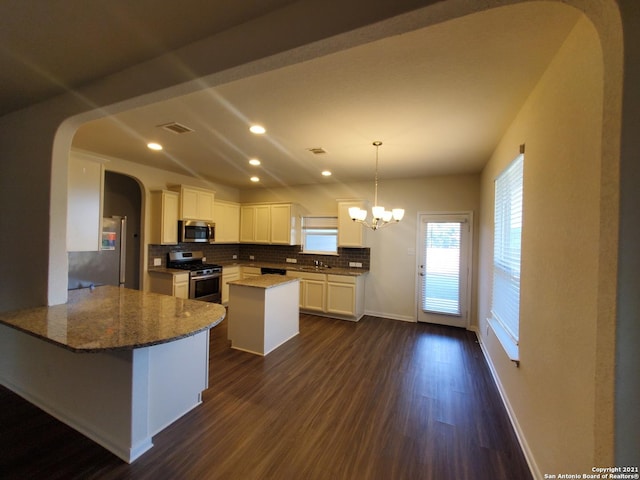 kitchen with stone countertops, arched walkways, decorative backsplash, dark wood-type flooring, and stainless steel appliances