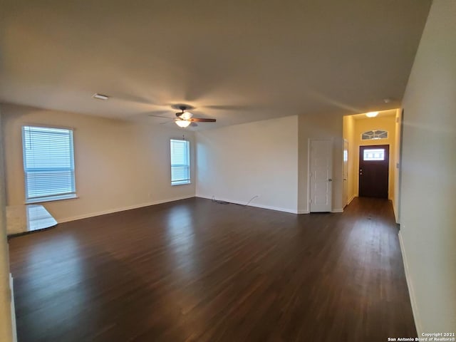 unfurnished living room featuring visible vents, dark wood-style flooring, a ceiling fan, and baseboards