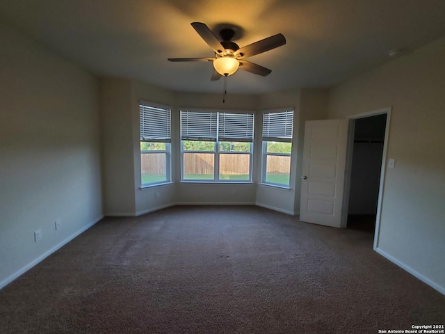 carpeted spare room featuring baseboards and a ceiling fan