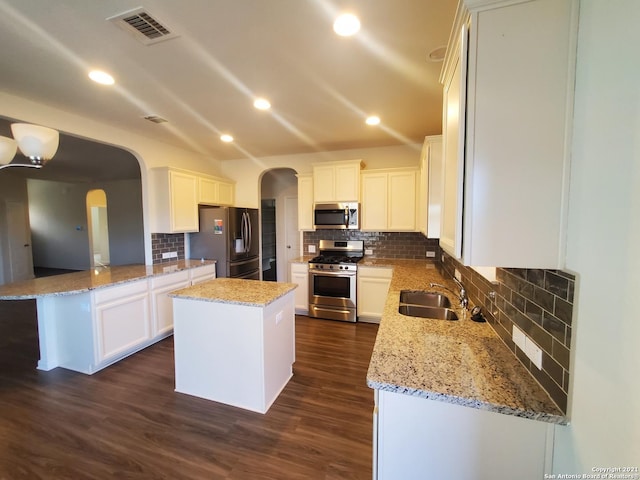 kitchen featuring visible vents, arched walkways, stainless steel appliances, and a sink