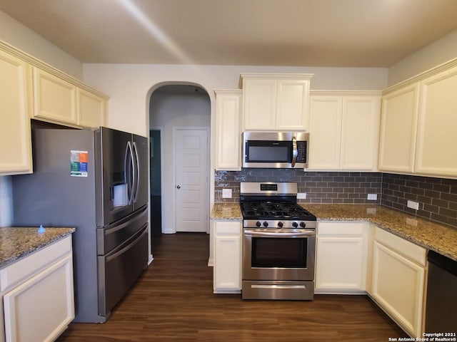 kitchen featuring appliances with stainless steel finishes, light stone counters, dark wood-style floors, and tasteful backsplash