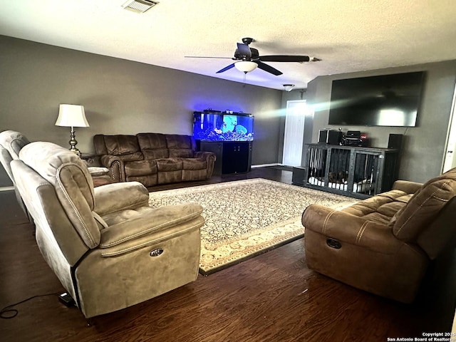 living room featuring visible vents, a textured ceiling, wood finished floors, and a ceiling fan