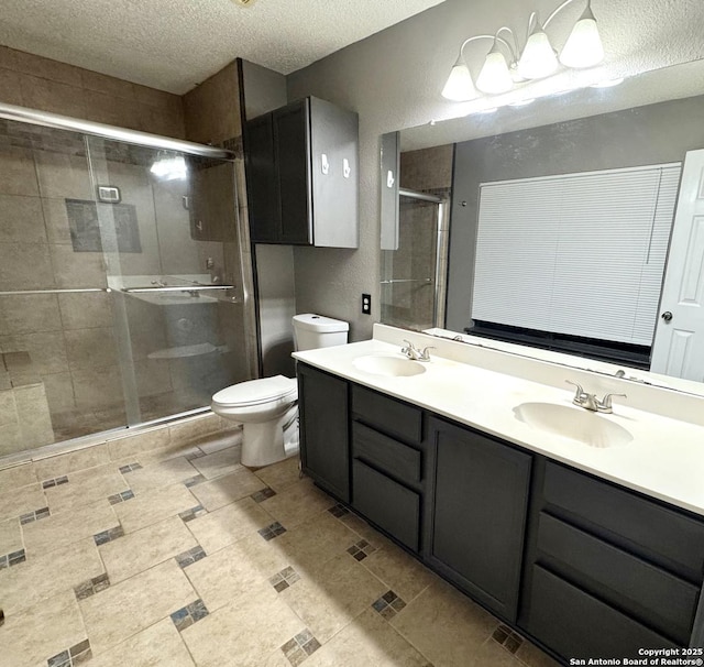 full bath featuring toilet, a shower stall, a textured ceiling, and a sink