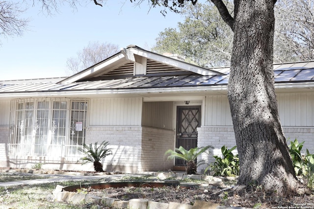 bungalow with metal roof, brick siding, and a standing seam roof