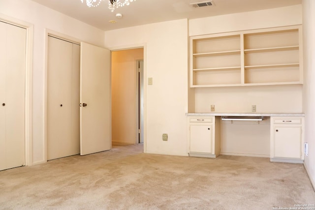 interior space featuring light carpet, visible vents, two closets, and built in study area