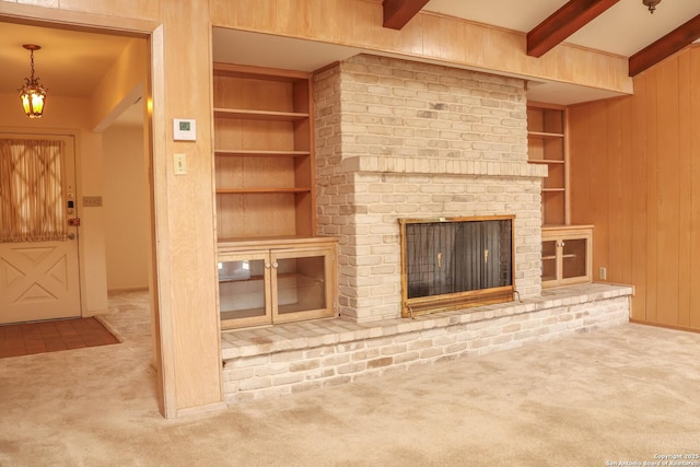 unfurnished living room featuring carpet floors, wooden walls, built in shelves, and beam ceiling