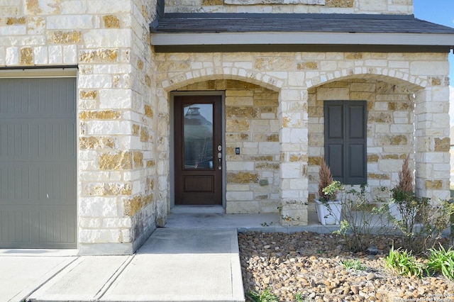 doorway to property with stone siding and an attached garage