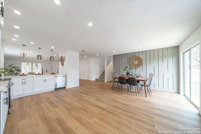 kitchen with open floor plan, stainless steel appliances, light countertops, and light wood-style flooring